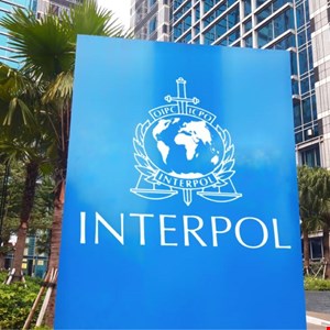 Interpol agents in a command center reviewing global cyber threat maps