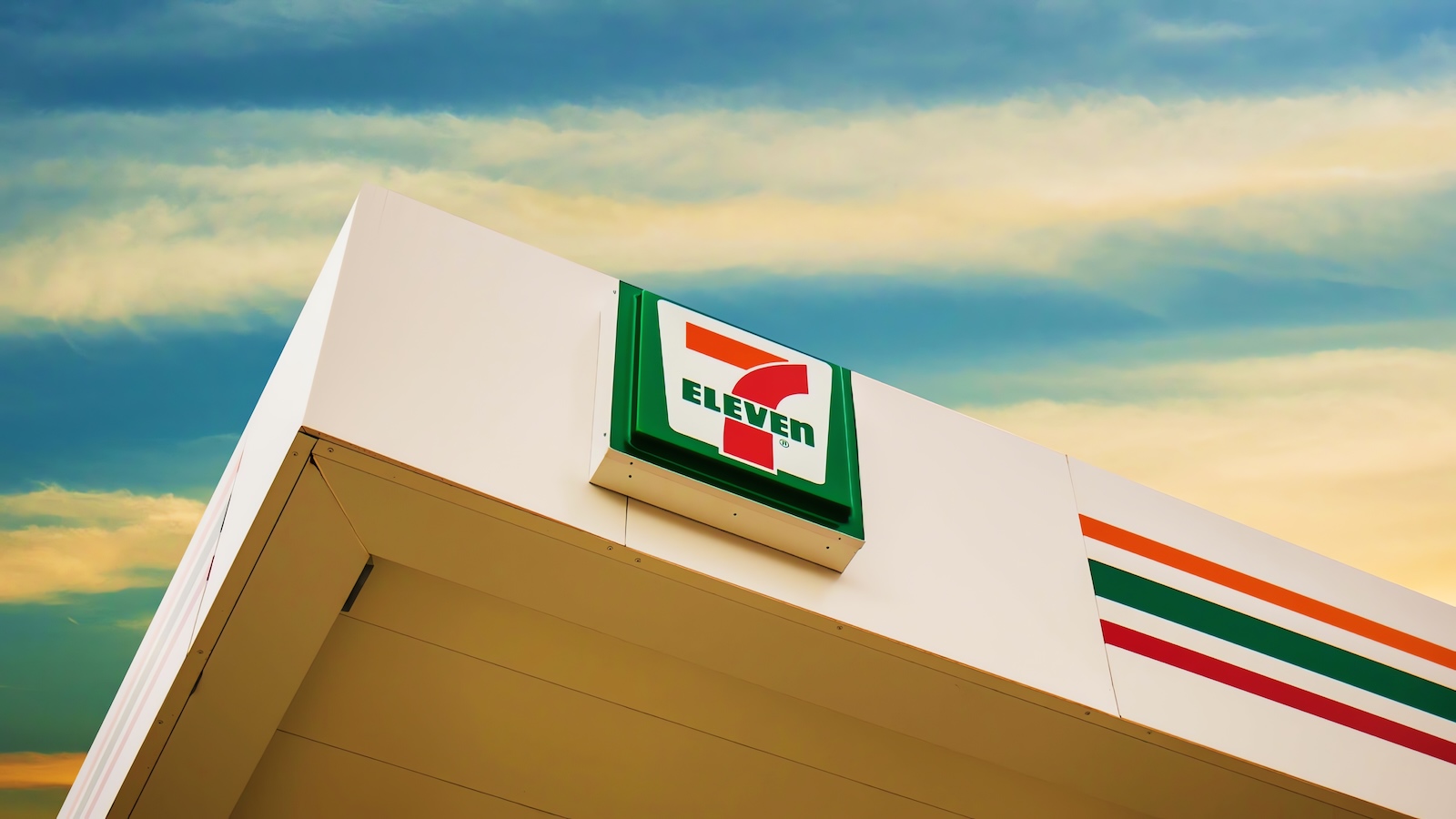 A 7-Eleven convenience store storefront at night with its iconic illuminated sign.