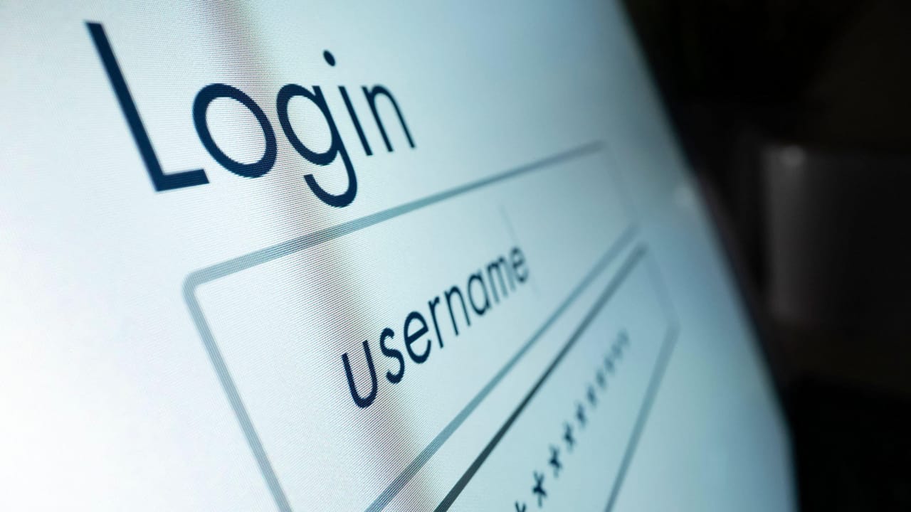 Hacker silhouette logging into corporate dashboard amid normal office logins